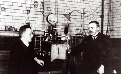 Hans Geiger and Ernest Rutherford display their equipment in their laboratory at Manchester University around 1908.